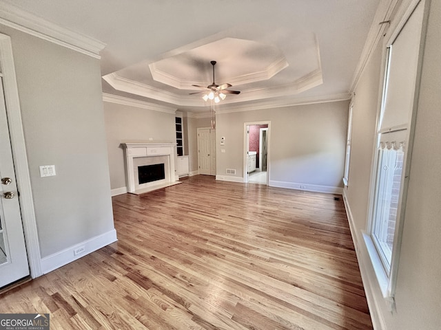 unfurnished living room with baseboards, a raised ceiling, a ceiling fan, and light wood-style flooring