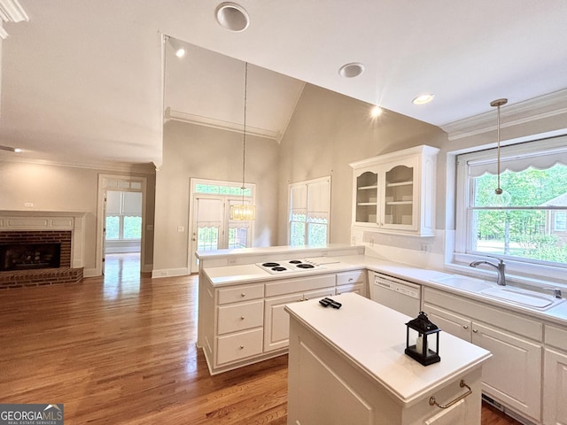 kitchen with white cabinetry, a sink, a kitchen island, open floor plan, and white appliances