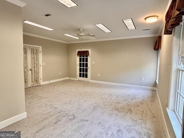 carpeted empty room featuring crown molding, a ceiling fan, and baseboards
