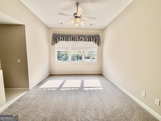 carpeted spare room featuring baseboards, visible vents, and ceiling fan