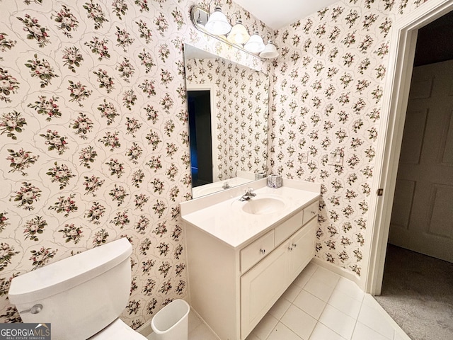 bathroom with wallpapered walls, baseboards, toilet, vanity, and tile patterned flooring