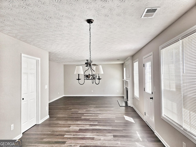 unfurnished dining area featuring an inviting chandelier, visible vents, dark wood-style flooring, and a textured ceiling