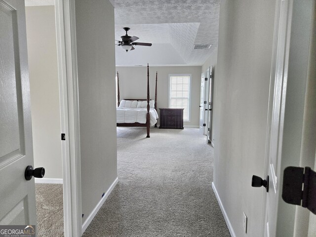 hall featuring baseboards, visible vents, a textured ceiling, and carpet