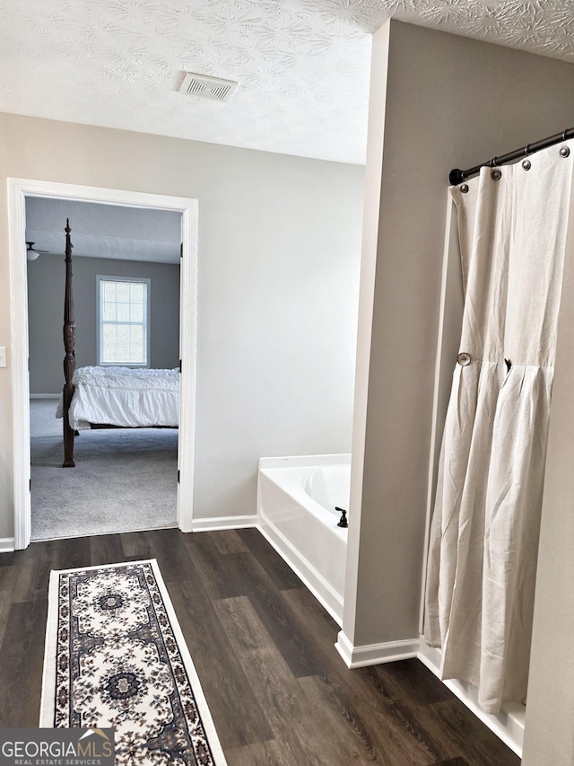 full bathroom featuring connected bathroom, visible vents, baseboards, a bath, and wood finished floors