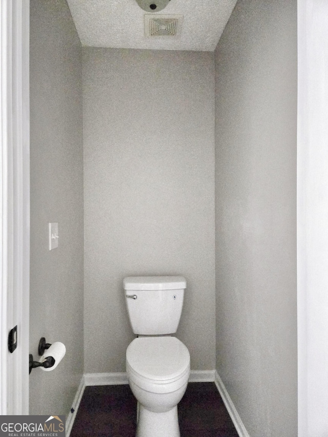 bathroom with baseboards, visible vents, and toilet