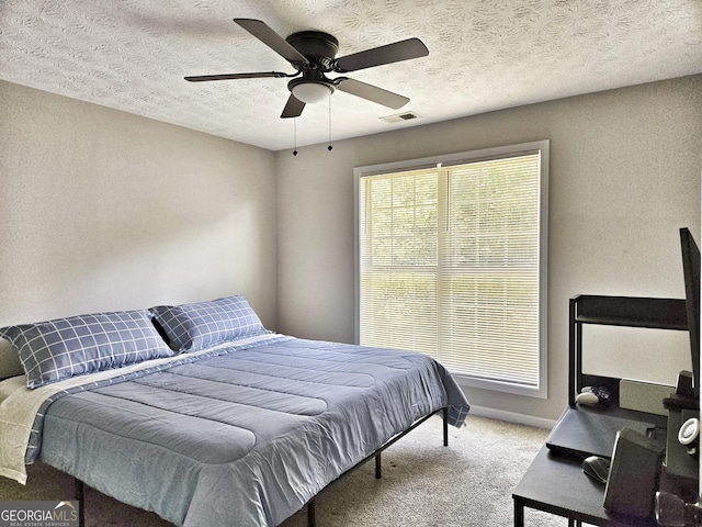 bedroom featuring carpet flooring, a textured ceiling, visible vents, and a ceiling fan