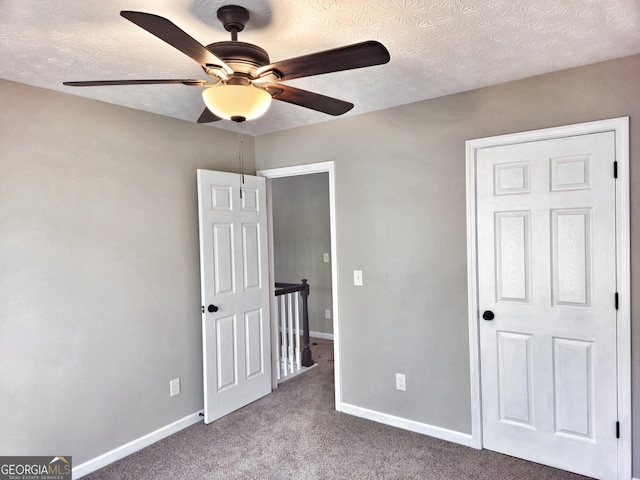 unfurnished bedroom featuring a textured ceiling, a ceiling fan, carpet floors, and baseboards