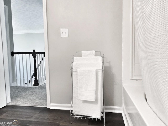 details featuring wood finished floors, shower / bath combination with curtain, and baseboards
