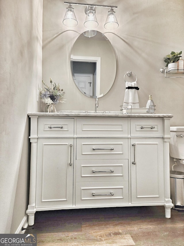 bathroom with toilet, wood finished floors, and vanity
