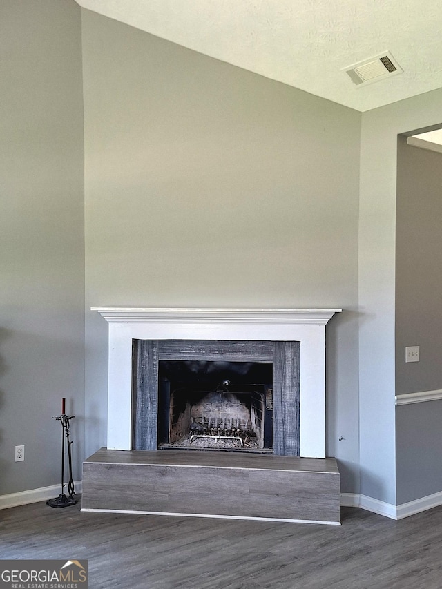 interior details with visible vents, baseboards, wood finished floors, and a fireplace