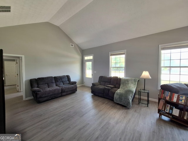 living area with wood finished floors, visible vents, high vaulted ceiling, and baseboards