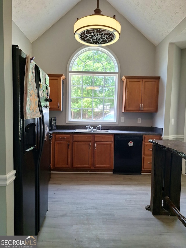 kitchen with black appliances, light wood finished floors, a sink, and lofted ceiling