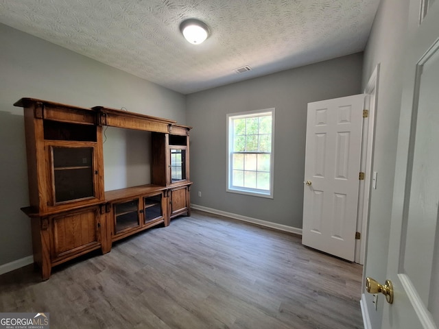 interior space with a textured ceiling, wood finished floors, and baseboards