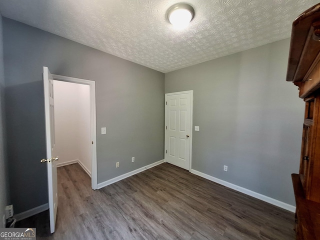 unfurnished bedroom featuring a textured ceiling, wood finished floors, and baseboards