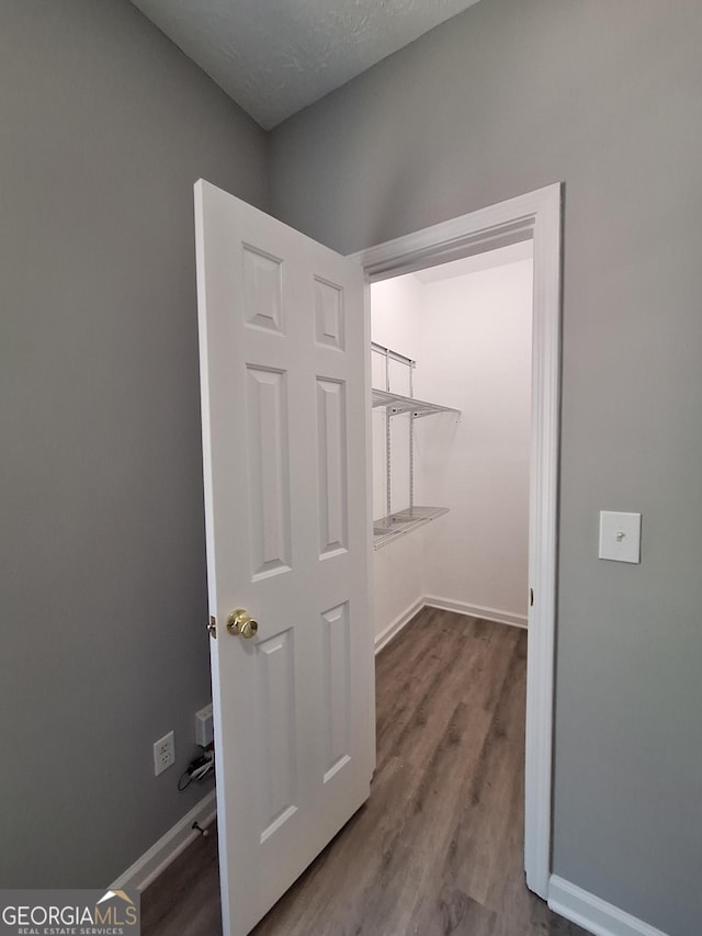walk in closet with wood finished floors
