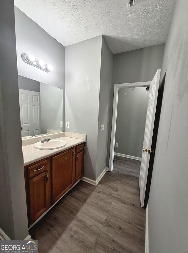 bathroom featuring baseboards, wood finished floors, a textured ceiling, and vanity