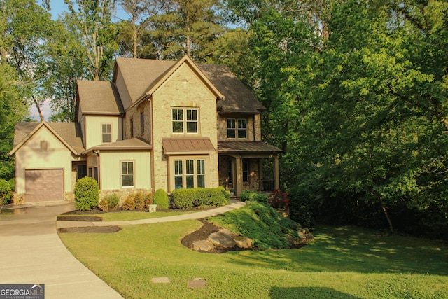 view of front of property featuring a garage, a front lawn, stone siding, roof with shingles, and driveway
