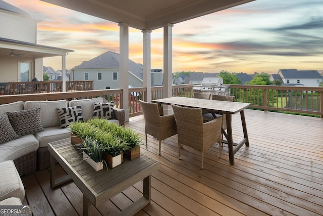 deck at dusk with a residential view, an outdoor kitchen, area for grilling, outdoor dining area, and an outdoor living space