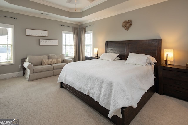 carpeted bedroom with a raised ceiling, ornamental molding, multiple windows, and visible vents