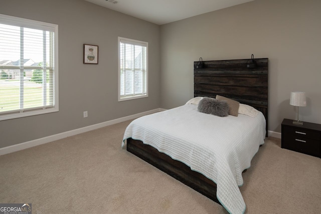 bedroom featuring baseboards, multiple windows, and light carpet