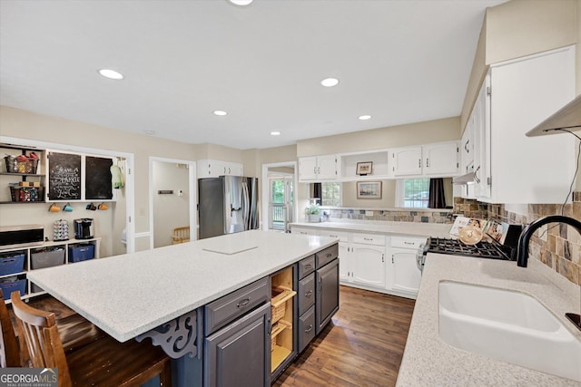 kitchen featuring appliances with stainless steel finishes, a sink, white cabinets, a kitchen island, and recessed lighting
