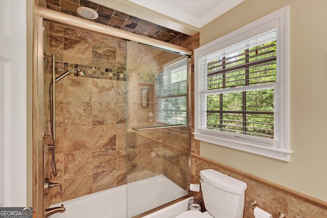 bathroom with toilet and bath / shower combo with glass door