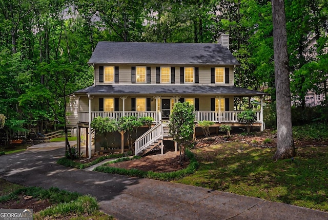 view of front facade with a porch, a chimney, driveway, and stairway