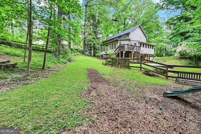 view of yard with a deck, stairway, and view of wooded area