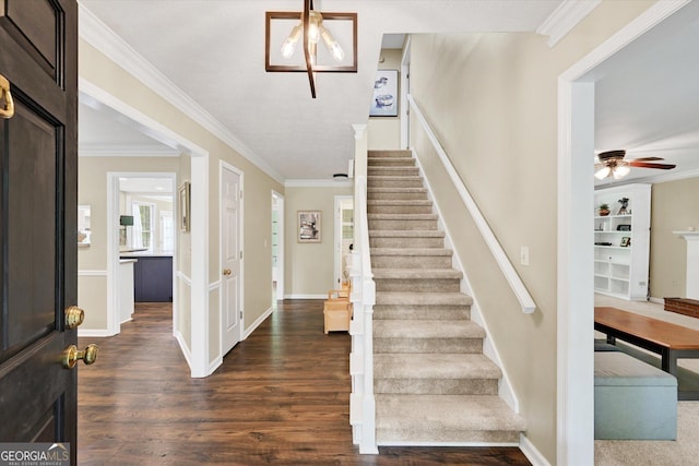 foyer with crown molding, a ceiling fan, dark wood-style flooring, and stairway