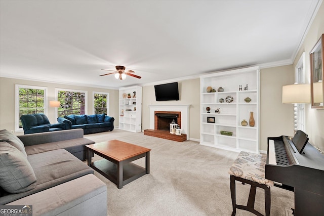 living area with ceiling fan, built in features, crown molding, a fireplace, and light colored carpet