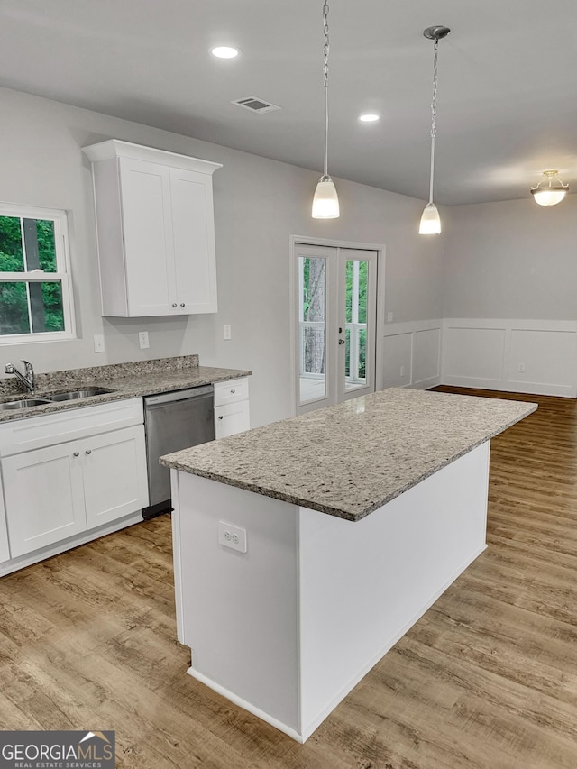 kitchen with a sink, a wealth of natural light, light stone countertops, and dishwasher