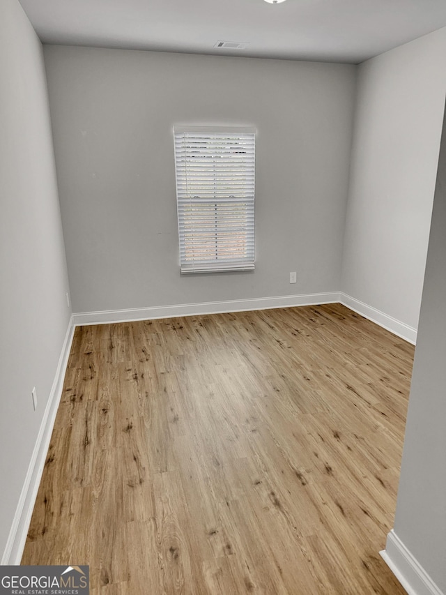 spare room with baseboards and wood finished floors