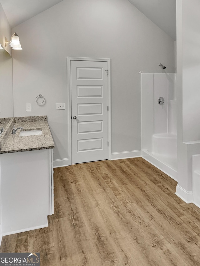 full bath with vaulted ceiling, wood finished floors, and a shower