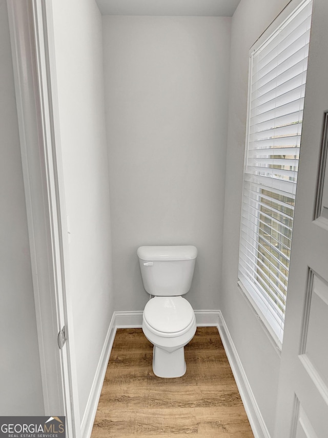 bathroom with baseboards, toilet, and wood finished floors