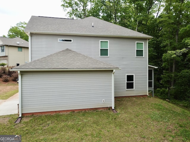 rear view of property with a lawn and roof with shingles
