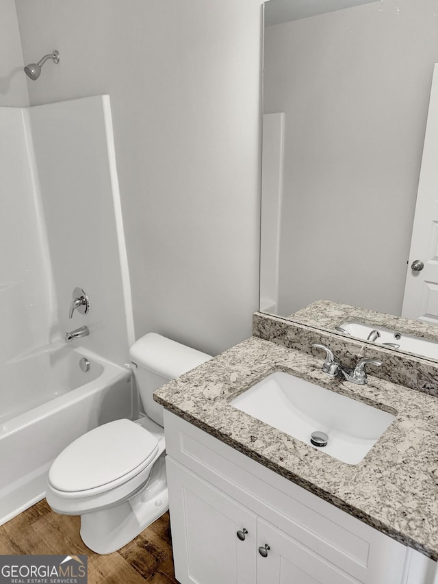 full bath with vanity, wood finished floors, bathtub / shower combination, and toilet