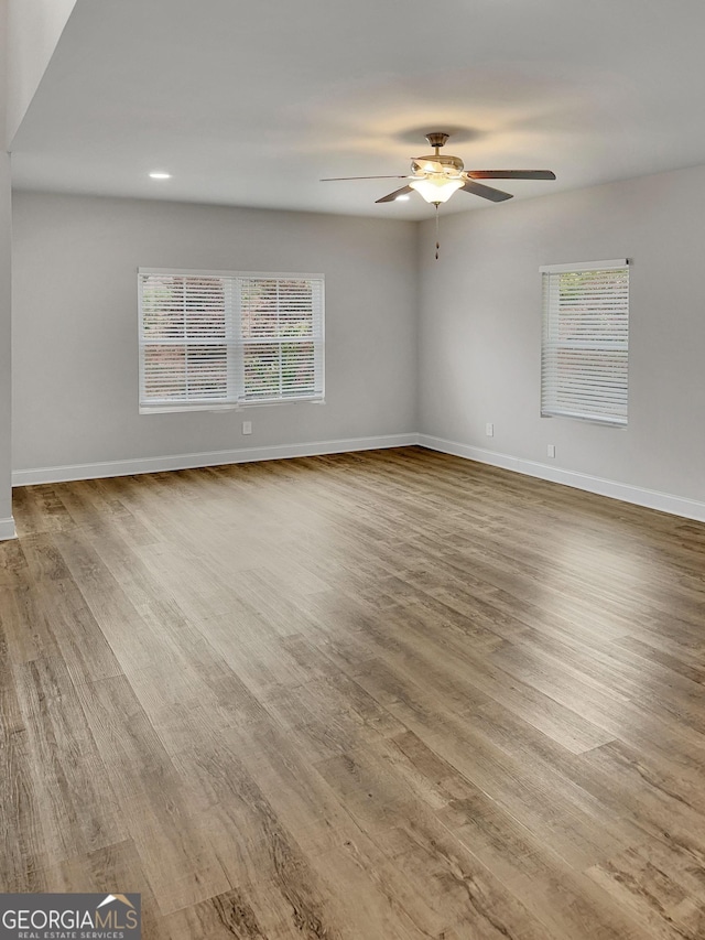 spare room with baseboards, plenty of natural light, and wood finished floors