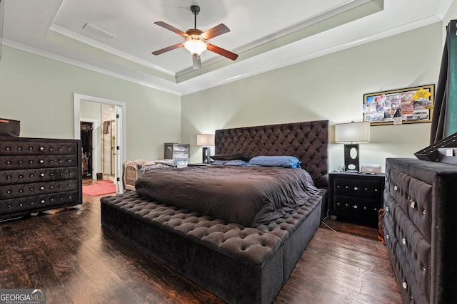 bedroom with visible vents, ornamental molding, a raised ceiling, and wood finished floors