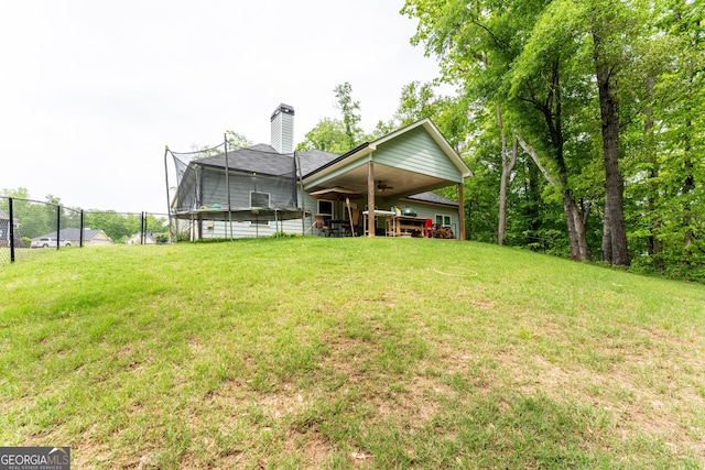 back of property with a lawn, a ceiling fan, fence, and a chimney