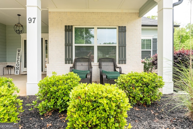 entrance to property with a porch and brick siding