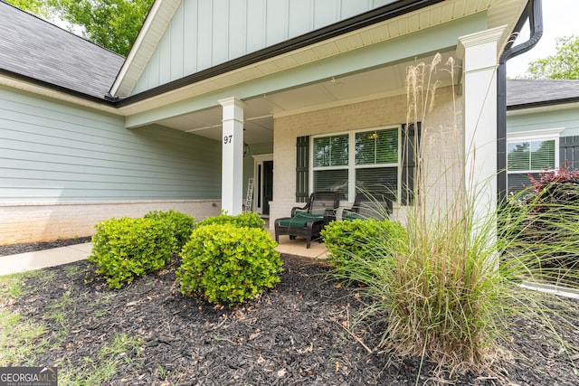 property entrance with board and batten siding, covered porch, and a shingled roof