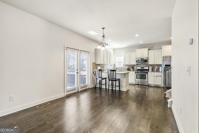 97 Fieldstone Ln, Dallas, GA 30132 - kitchen featuring appliances with stainless steel finishes, decorative backsplash, a kitchen breakfast bar, dark wood-type flooring, and white cabinets