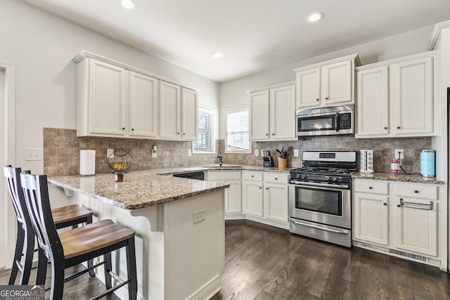 97 Fieldstone Ln, Dallas, GA 30132 - kitchen with stainless steel appliances, a sink, a peninsula, dark wood finished floors, and white cabinetry