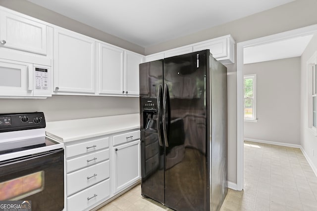 kitchen with range with electric stovetop, white microwave, light countertops, white cabinetry, and black fridge