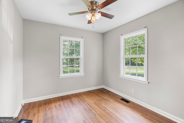 unfurnished room with baseboards, ceiling fan, wood-type flooring, and visible vents