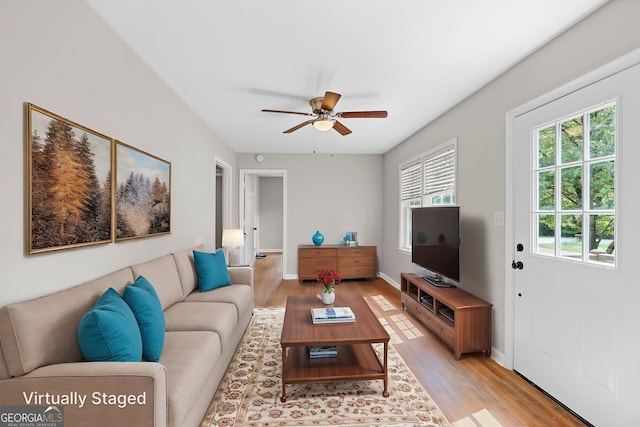 living room featuring baseboards, a ceiling fan, and light wood finished floors