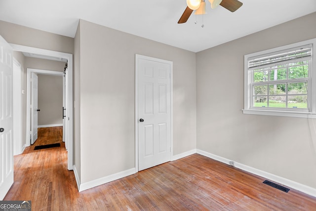 unfurnished bedroom with visible vents, baseboards, ceiling fan, and wood finished floors