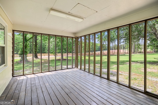 unfurnished sunroom with hardwood / wood-style flooring, a healthy amount of sunlight, and a deck