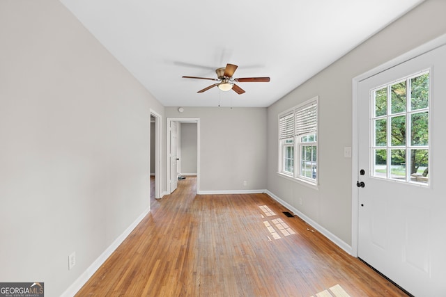 interior space featuring baseboards, a ceiling fan, visible vents, and light wood-type flooring