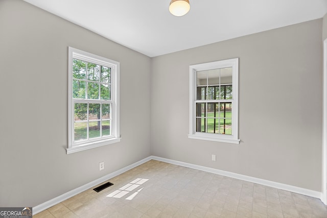 spare room featuring baseboards, light tile patterned floors, a healthy amount of sunlight, and visible vents
